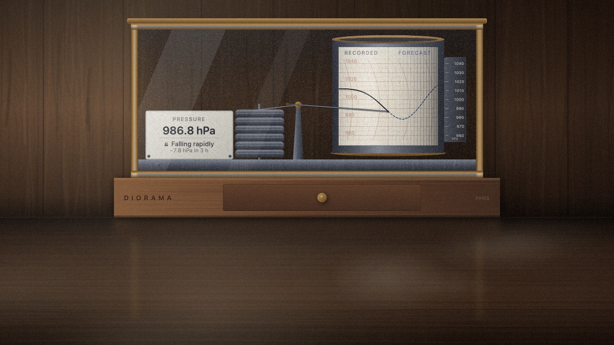 A brass-and-glass recording barometer standing on a polished walnut table, its paper drum carrying a falling pressure trace with the pen resting on it.
